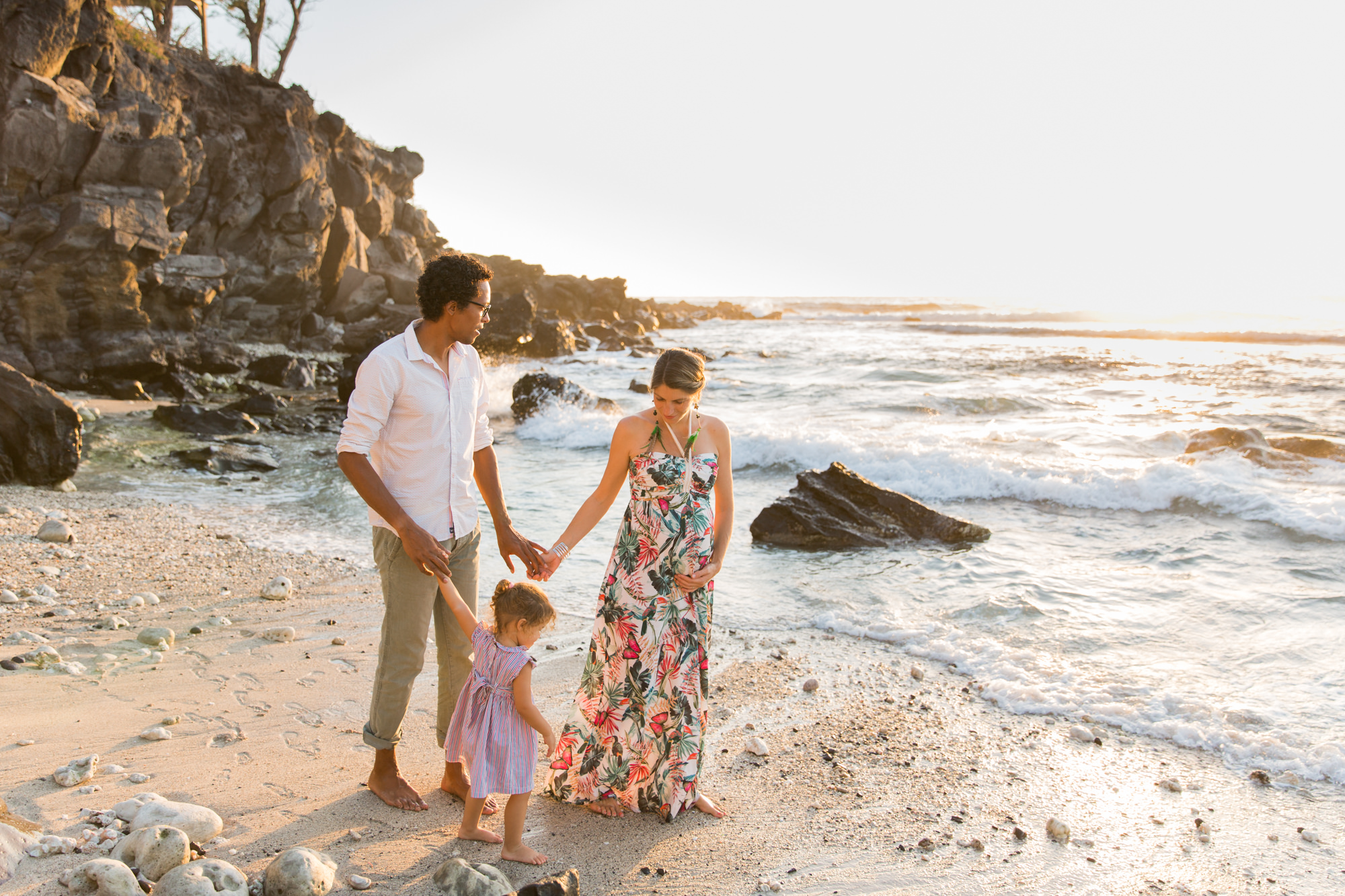 Une famille qui marche sur le sable d'une plage de la réunion au coucher du soleil Futurs parents immortalisés par une photographe de grossesse professionnelle