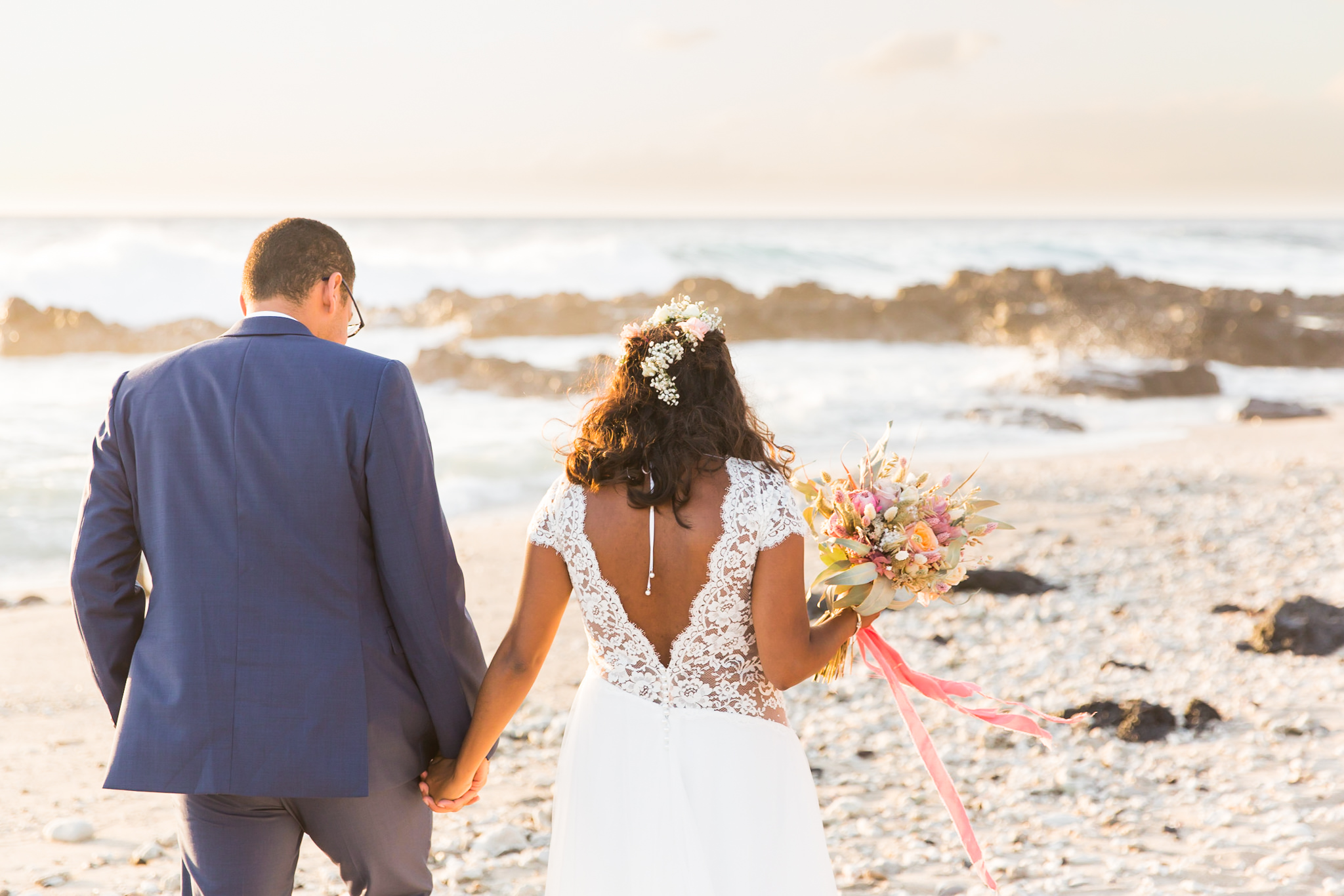 Un couple qui marche sur la plage de la Réunion le jour de leur mariage champêtre chic
