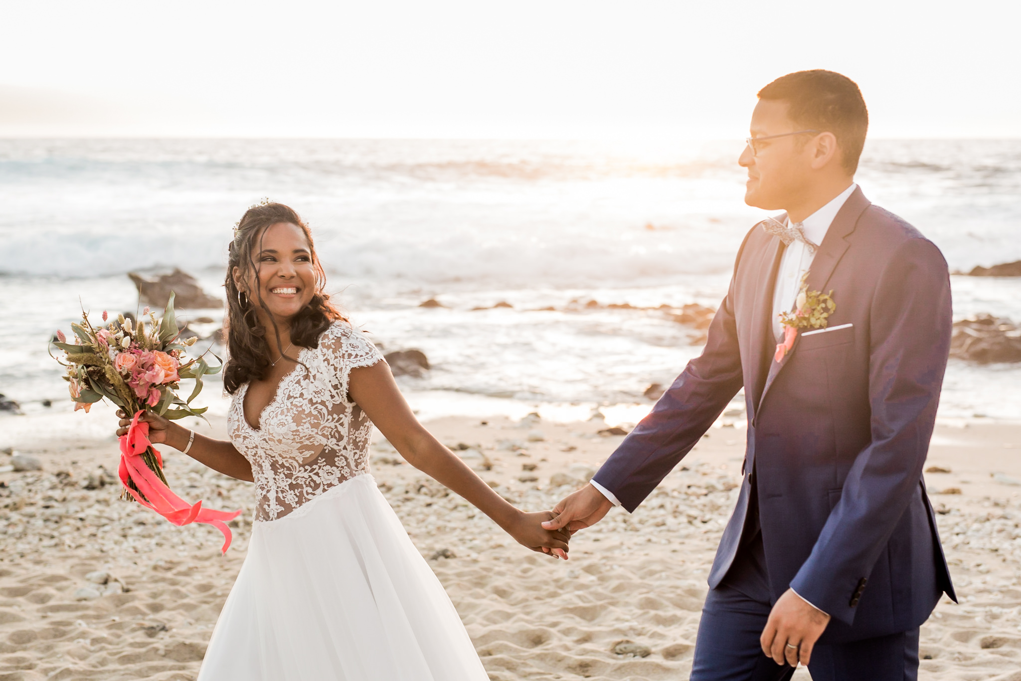 Un couple de marié sur la plage au coucher du soleil avec un bouquet champêtre chic
