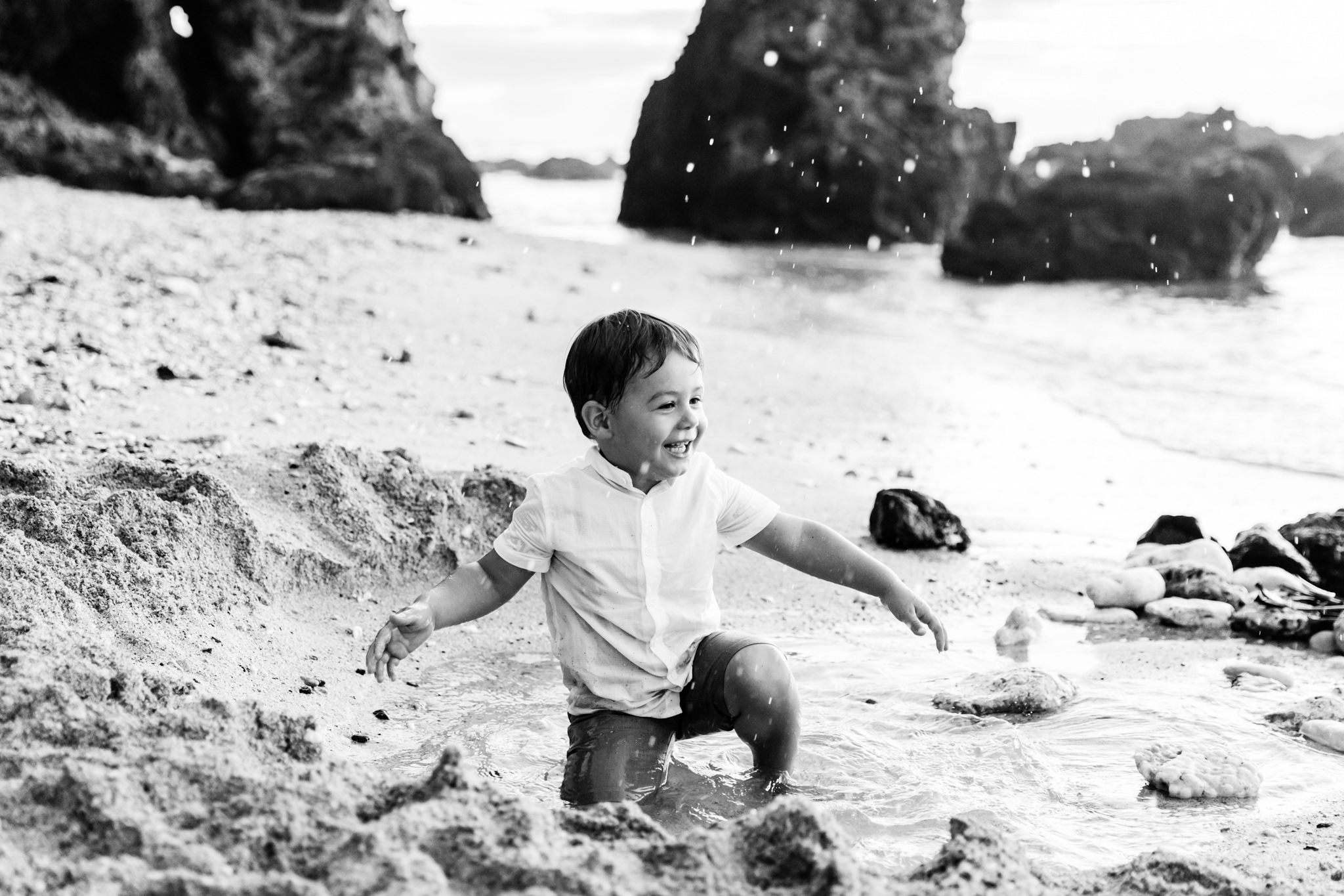 Une photo en noir et blanc d'un petit garçon qui joue dans l'eau sur une plage de la Réunion