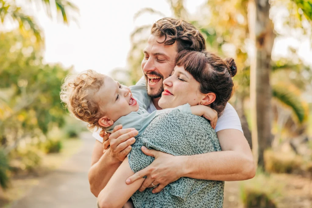 Un papa, une maman et leur enfant, qui se font un câlin à sainte marie